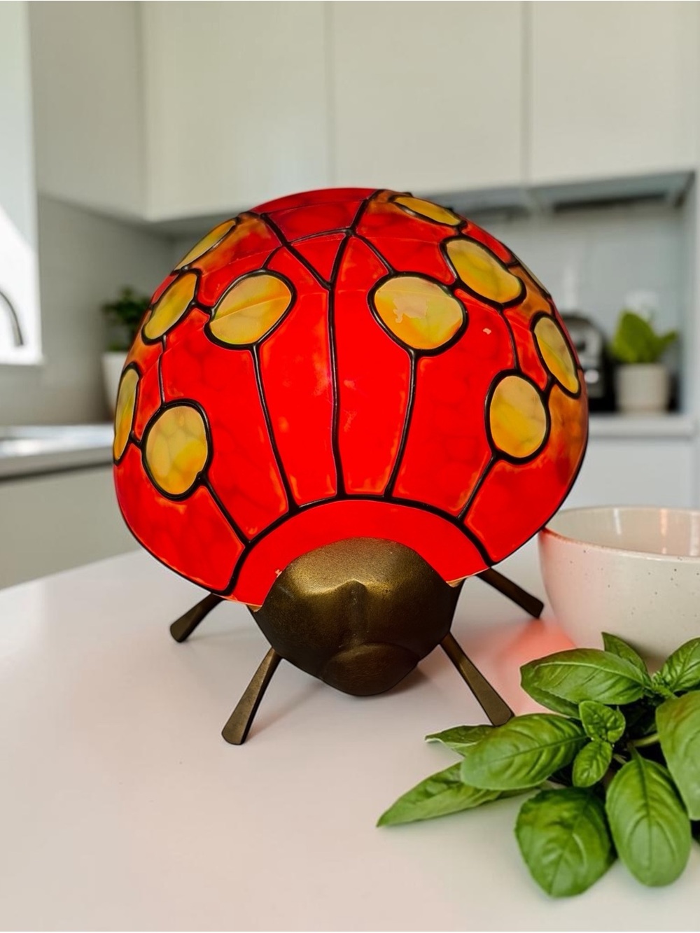 Ladybug-shaped lamp painted in red with yellow spots and a bronze finish
